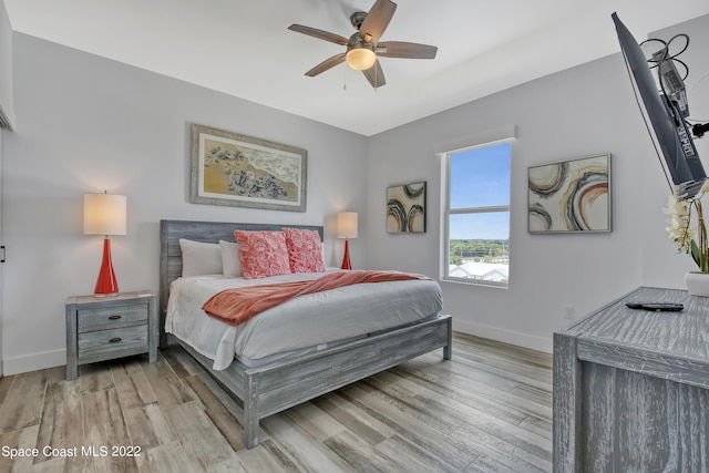 bedroom featuring baseboards, light wood-style flooring, and a ceiling fan