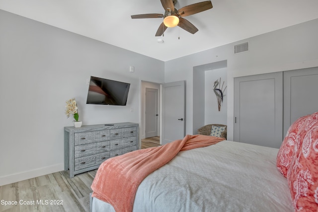bedroom with a closet, visible vents, light wood finished floors, baseboards, and ceiling fan