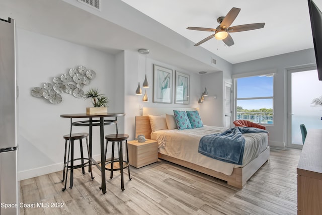 bedroom with freestanding refrigerator, baseboards, light wood finished floors, and visible vents