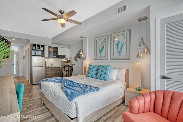 bedroom featuring light hardwood / wood-style floors, stainless steel refrigerator, and ceiling fan