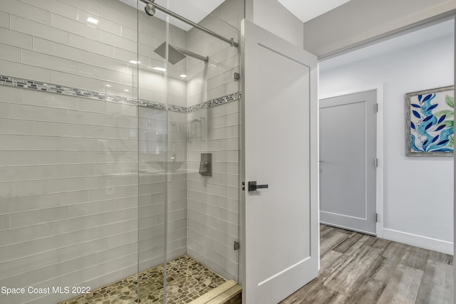 full bath with baseboards, wood finished floors, and a stall shower