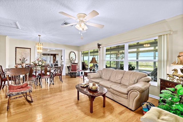 living room with ceiling fan, plenty of natural light, light hardwood / wood-style floors, and a textured ceiling