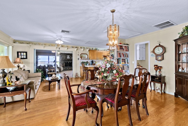 dining space featuring ornamental molding, plenty of natural light, ceiling fan with notable chandelier, and light wood-type flooring