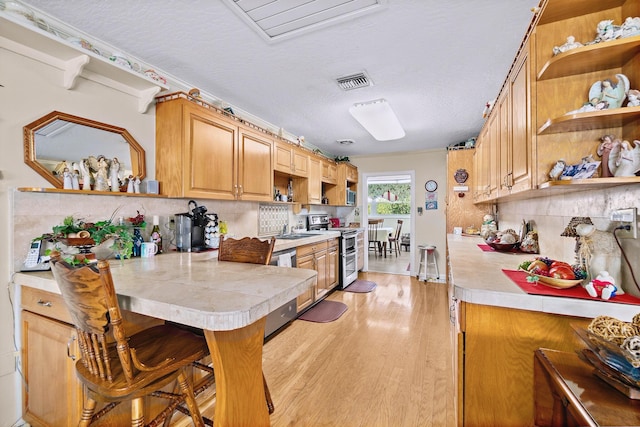 kitchen featuring sink, light hardwood / wood-style flooring, appliances with stainless steel finishes, a kitchen breakfast bar, and decorative backsplash