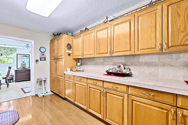 kitchen featuring tasteful backsplash, tile counters, a textured ceiling, and light hardwood / wood-style floors