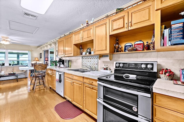 kitchen with sink, a textured ceiling, light wood-type flooring, stainless steel appliances, and decorative backsplash