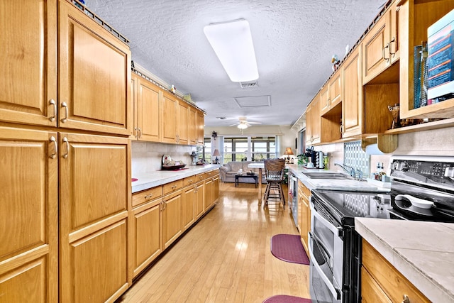 kitchen with sink, light wood-type flooring, backsplash, range with two ovens, and a textured ceiling