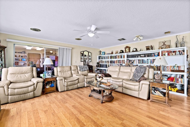 living room with ornamental molding, a textured ceiling, and light hardwood / wood-style floors