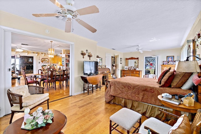 bedroom with crown molding, ceiling fan with notable chandelier, light hardwood / wood-style floors, and a textured ceiling