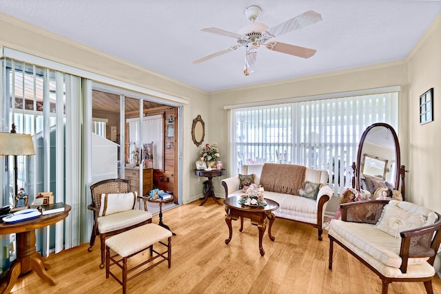 living room with ceiling fan, ornamental molding, and light hardwood / wood-style flooring