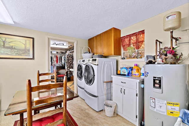 laundry area with cabinets, electric water heater, washing machine and dryer, and a textured ceiling