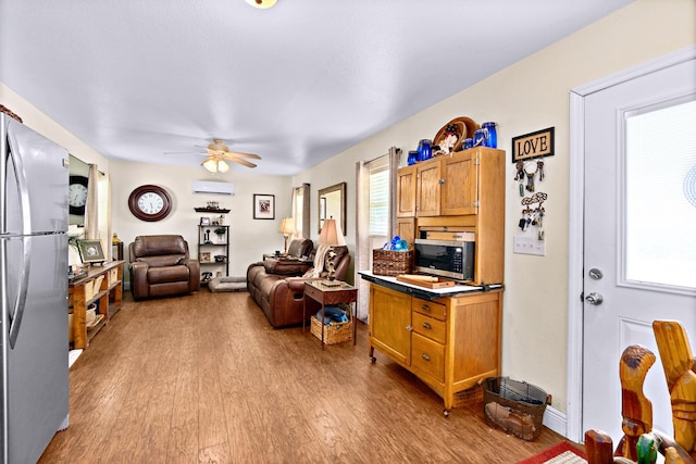 kitchen featuring light wood-type flooring, a wall mounted air conditioner, a wealth of natural light, and appliances with stainless steel finishes