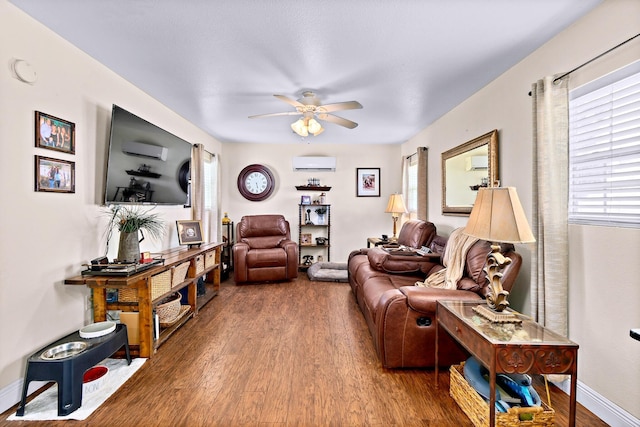 living room with ceiling fan, a healthy amount of sunlight, wood-type flooring, and a wall unit AC