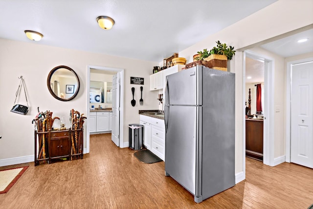 kitchen featuring white cabinets, stainless steel refrigerator, and light hardwood / wood-style floors