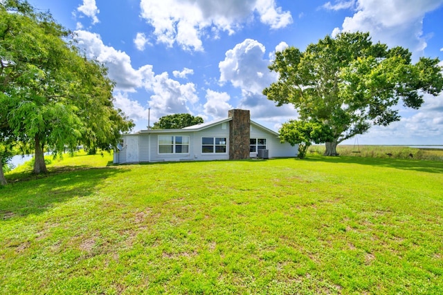 back of house with cooling unit and a yard