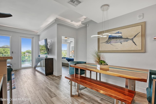 dining area with light wood finished floors, baseboards, and visible vents