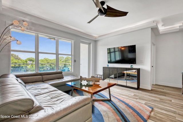 living area with baseboards, wood finished floors, and a ceiling fan