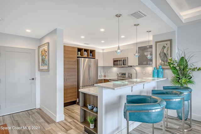 kitchen featuring open shelves, appliances with stainless steel finishes, a peninsula, visible vents, and decorative backsplash