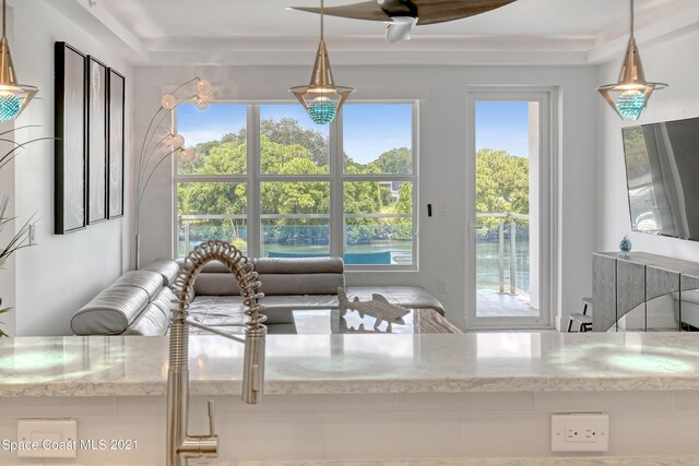 interior space with pendant lighting, light stone countertops, and a raised ceiling