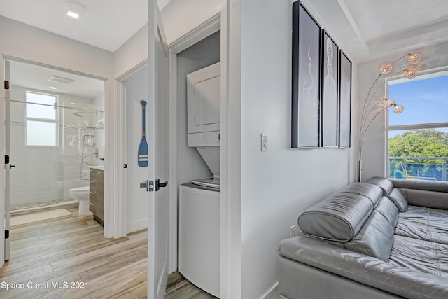 laundry room with light wood finished floors, stacked washer and dryer, and laundry area