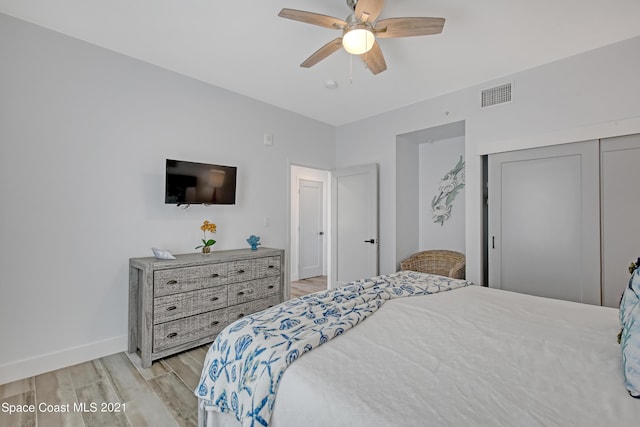 bedroom with a closet, visible vents, light wood finished floors, baseboards, and ceiling fan