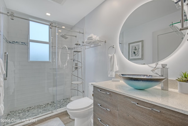 bathroom with vanity, toilet, a shower stall, and wood finished floors