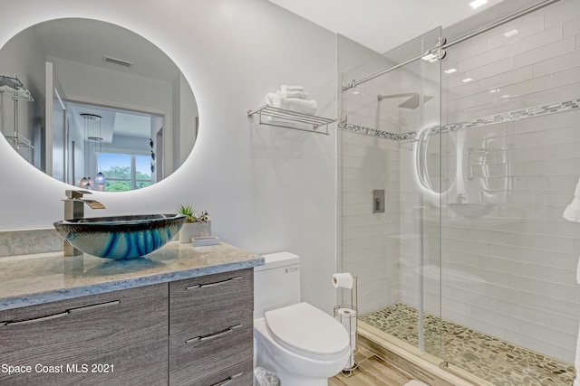 bathroom featuring vanity, a shower with door, and toilet