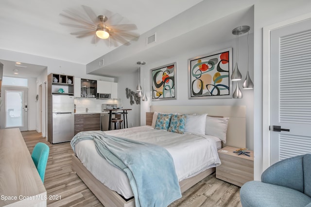 bedroom with light wood finished floors, visible vents, and stainless steel fridge