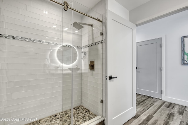 bathroom with a shower with shower door and hardwood / wood-style floors