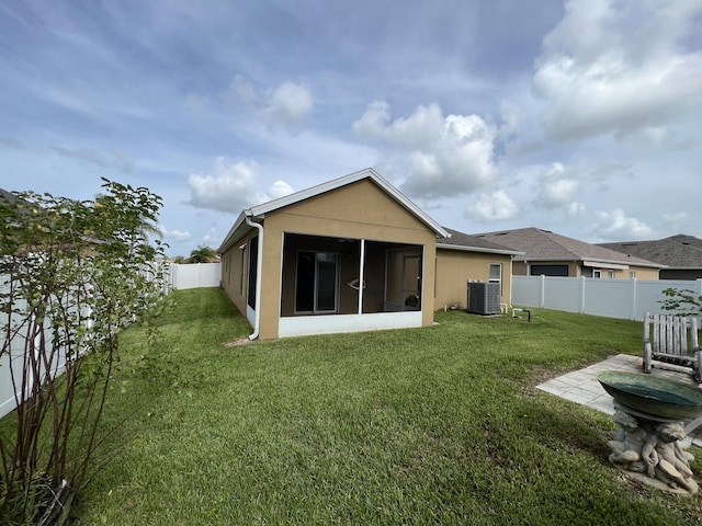 rear view of property featuring cooling unit, a sunroom, and a yard