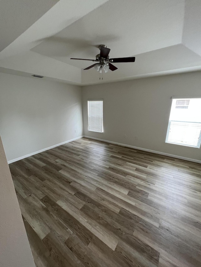 empty room featuring dark hardwood / wood-style flooring, a healthy amount of sunlight, and ceiling fan