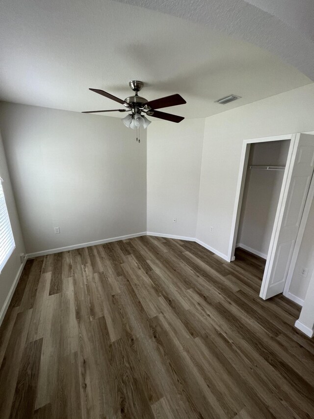 unfurnished bedroom with a textured ceiling, dark hardwood / wood-style flooring, ceiling fan, and a closet