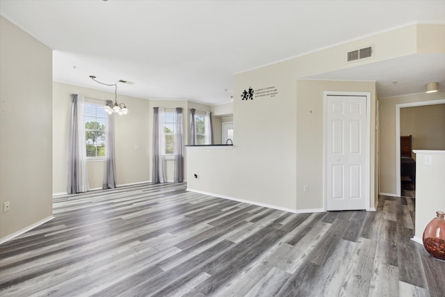 unfurnished living room with crown molding, a chandelier, and hardwood / wood-style floors