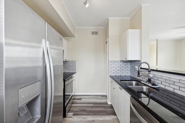 kitchen featuring dark wood-type flooring, sink, appliances with stainless steel finishes, dark stone counters, and white cabinets