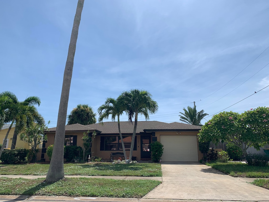 ranch-style home with a garage and a front lawn