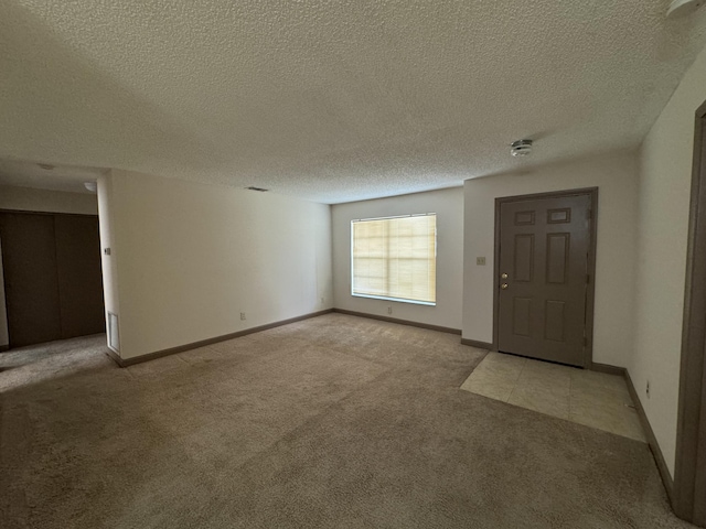 foyer entrance featuring light carpet and a textured ceiling