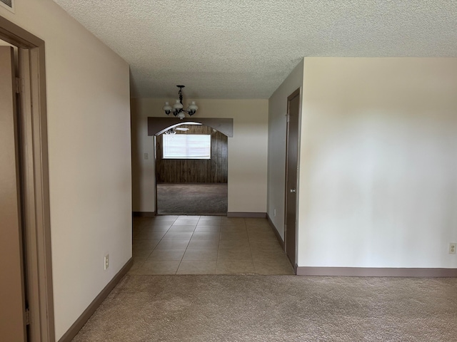 hallway featuring carpet flooring, a chandelier, and a textured ceiling