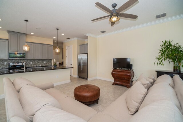 tiled living room with sink, ceiling fan, and ornamental molding