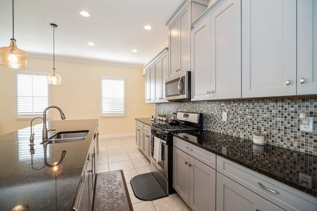 kitchen with dark stone countertops, tasteful backsplash, light tile patterned floors, stainless steel appliances, and sink