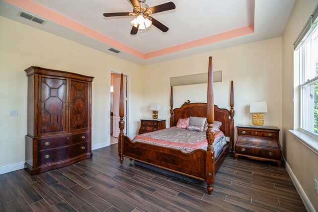 bedroom with dark wood-type flooring, ceiling fan, and a raised ceiling