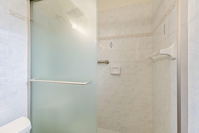 bathroom with a tile shower and toilet