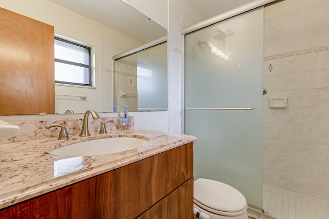 bathroom featuring a shower with door, toilet, and vanity