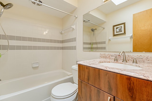 full bathroom with tiled shower / bath, a skylight, vanity, and toilet