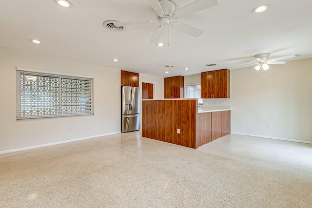 unfurnished living room with ceiling fan and a wealth of natural light