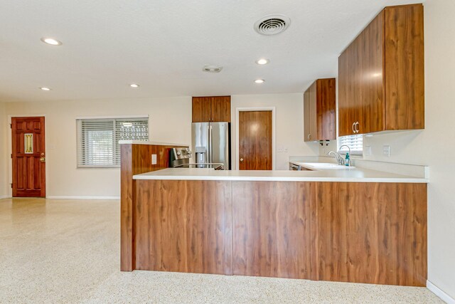 kitchen featuring kitchen peninsula, sink, stainless steel refrigerator with ice dispenser, and plenty of natural light