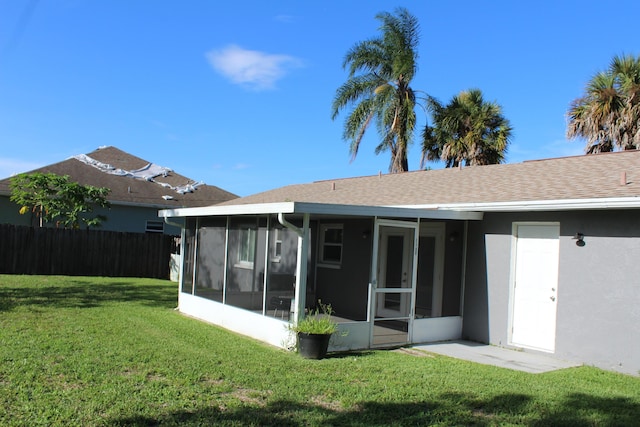 back of property with a sunroom and a lawn