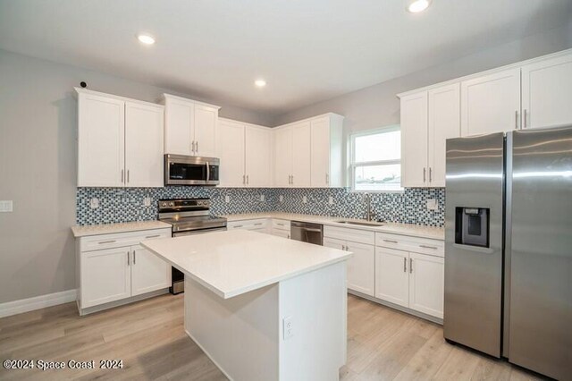 kitchen with light wood-type flooring, appliances with stainless steel finishes, and white cabinetry