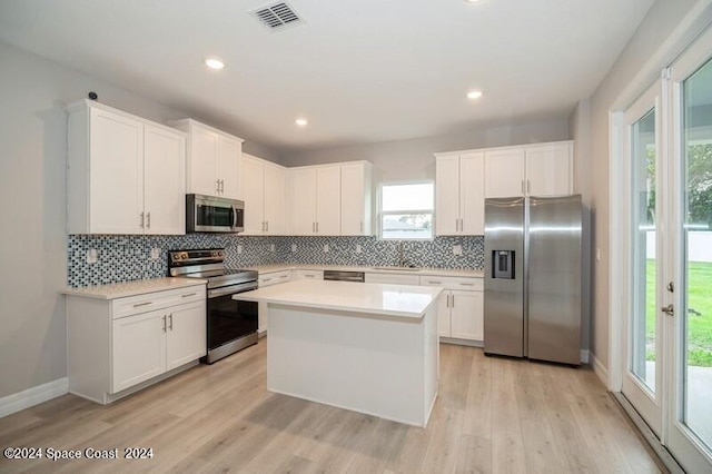 kitchen with white cabinets, light wood-type flooring, appliances with stainless steel finishes, and a kitchen island