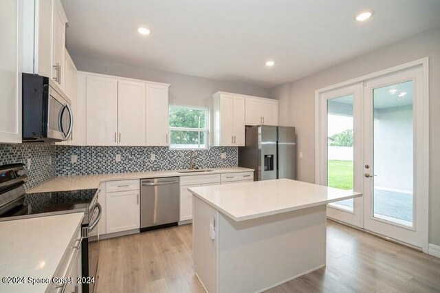 kitchen featuring white cabinets, a kitchen island, stainless steel appliances, and a healthy amount of sunlight