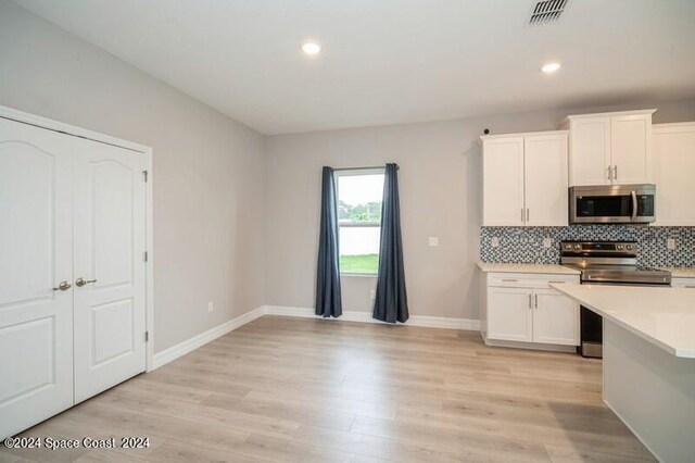 kitchen with stainless steel appliances, light wood-type flooring, white cabinetry, and tasteful backsplash